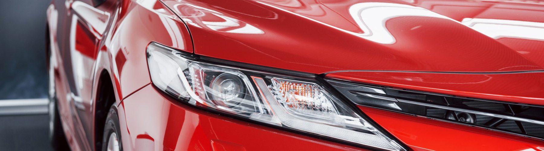 Headlights of the new red car, in the car dealership